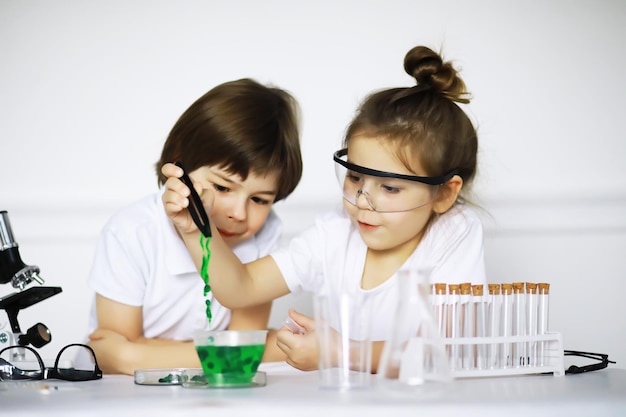 Deux enfants mignons à la leçon de chimie faisant des expériences isolées sur fond blanc