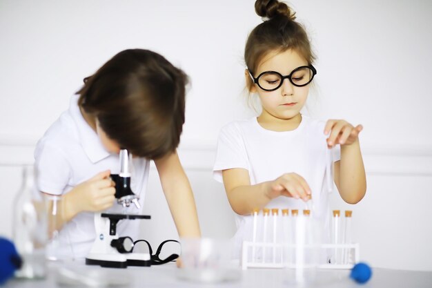 Deux enfants mignons à la leçon de chimie faisant des expériences isolées sur fond blanc