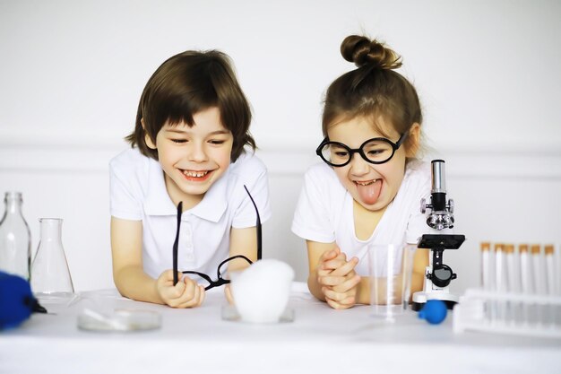 Deux enfants mignons à la leçon de chimie faisant des expériences isolées sur fond blanc