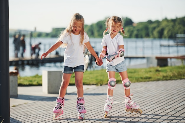 Deux enfants mignons en patins à roulettes dans le parc pendant la journée.