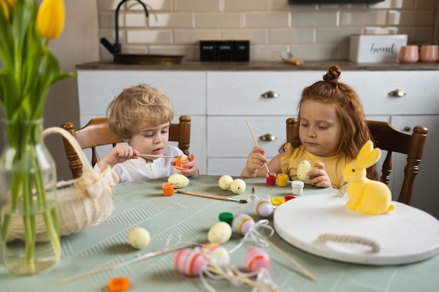 Deux enfants pendant la peinture des oeufs de PâquesxA