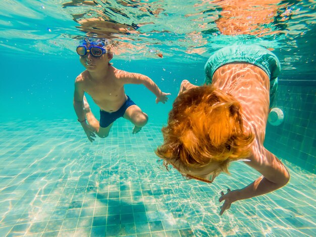 Deux enfants plongeant dans des masques sous l'eau dans la piscine.