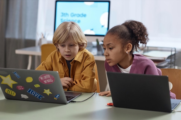 Photo deux enfants qui utilisent un ordinateur portable en classe