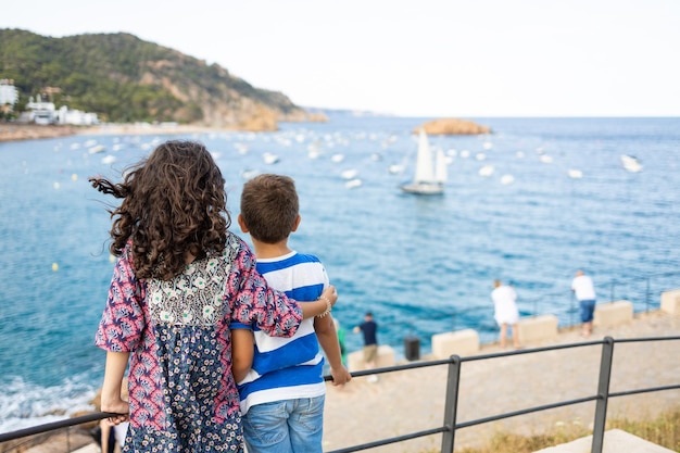 Photo deux enfants regardent la mer en arrière.