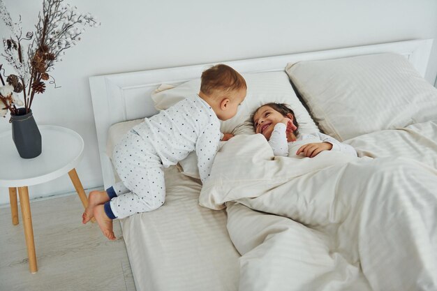 Deux enfants s'amusent en se couchant sur le lit Intérieur et design d'une belle chambre moderne pendant la journée