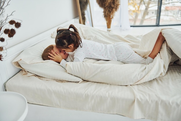 Deux enfants s'amusent en se couchant sur le lit Intérieur et design d'une belle chambre moderne pendant la journée