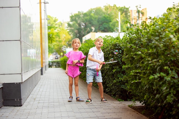 Deux enfants souriants, garçon et fille courant ensemble en ville, ville en journée d'été