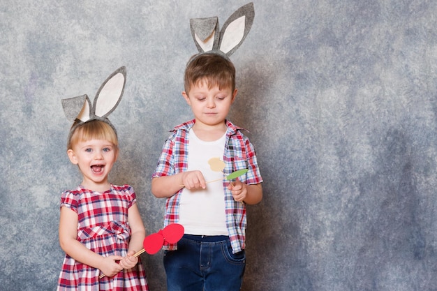 Deux enfants tiennent dans leurs mains des œufs de Pâques colorés en carton Espace de copie