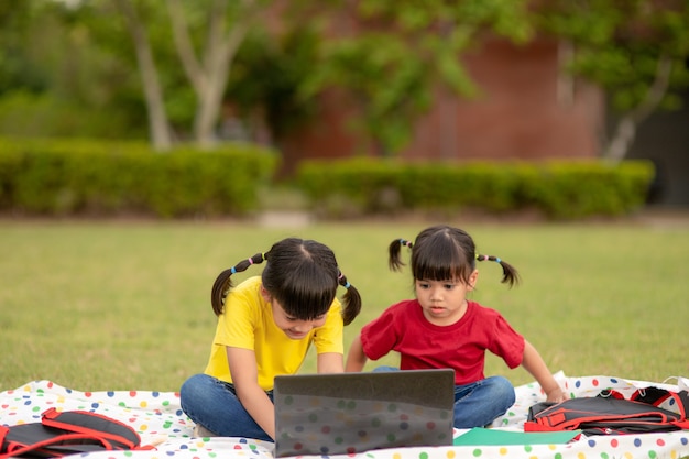 Deux étudiantes asiatiques étudient en ligne avec un enseignant par appel vidéo ensemble.