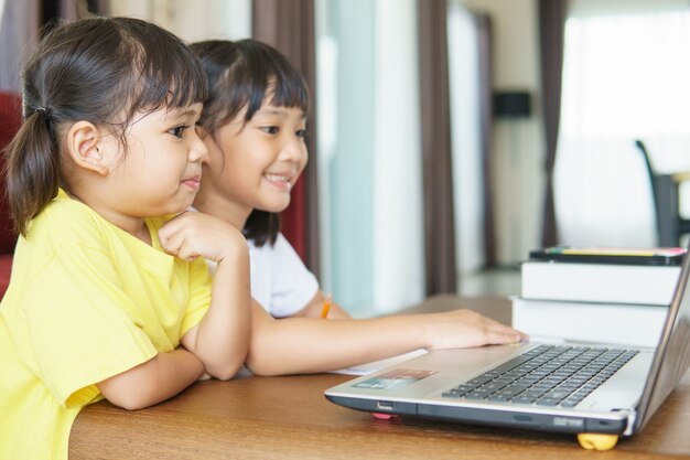 deux étudiantes asiatiques étudient en ligne avec un enseignant par appel vidéo ensemble