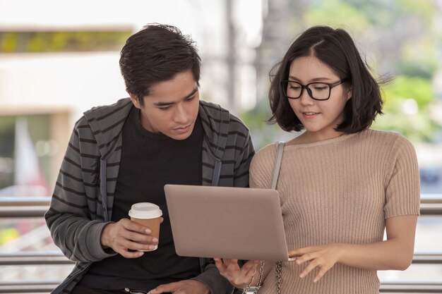 Deux étudiants étudient avec un ordinateur portable à l&#39;extérieur