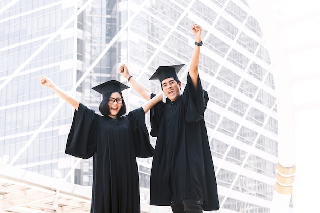 Deux étudiants heureux célébrant l&#39;obtention du diplôme sur fond de construction de campus