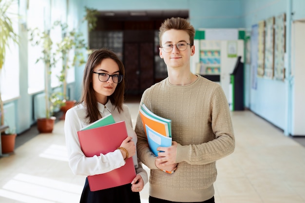 Deux étudiants heureux debout sur le campus en regardant la caméra