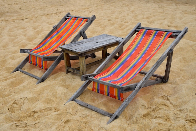 Deux fauteuils en bois colorés sur une plage de sable