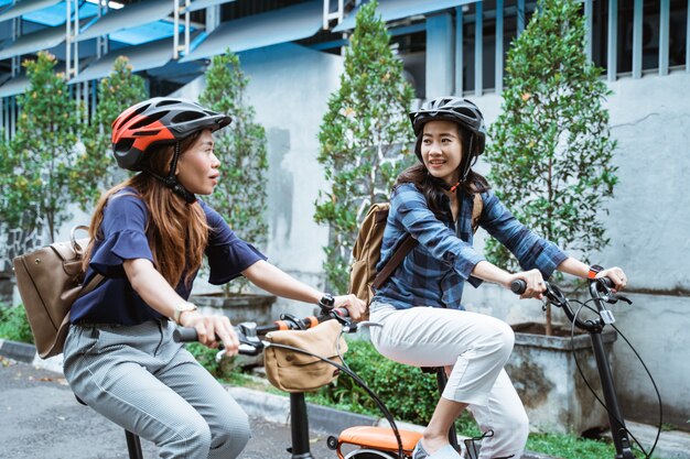 Deux femme asiatique portant un casque et des sacs de transport à vélo