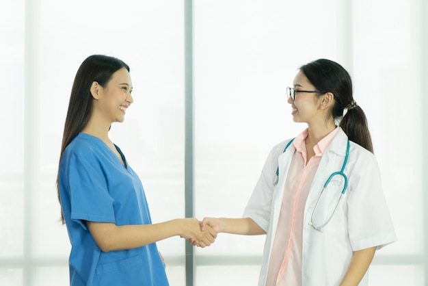 Deux femme médecin asiatique debout ensemble et se serrant la main.