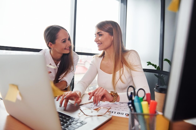 Deux femmes adultes en vêtements formels sont à l'intérieur dans le bureau ensemble