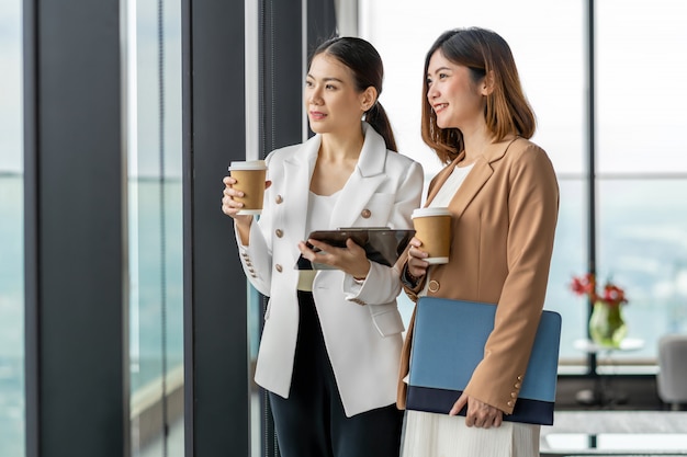 Deux femmes d'affaires asiatiques parler pendant la pause-café dans un bureau moderne ou un espace de coworking