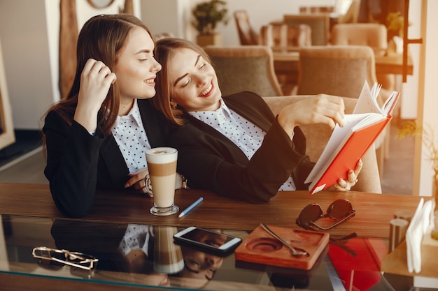 deux femmes d&#39;affaires jeunes et élégantes, assis au bureau du café et de travail