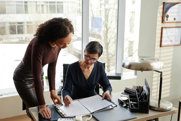 Deux femmes d'affaires professionnelles élégantes discutant de documents au bureau