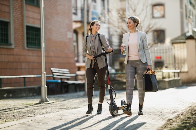 Deux femmes d'affaires prospères discutant en se promenant dans la ville.
