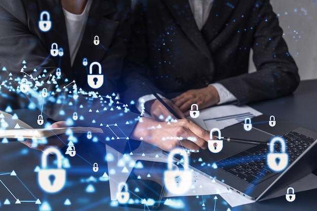 Deux femmes d'affaires travaillant sur le projet visant à protéger la cybersécurité de la société internationale Padlock Hologram icônes sur la table avec des documents