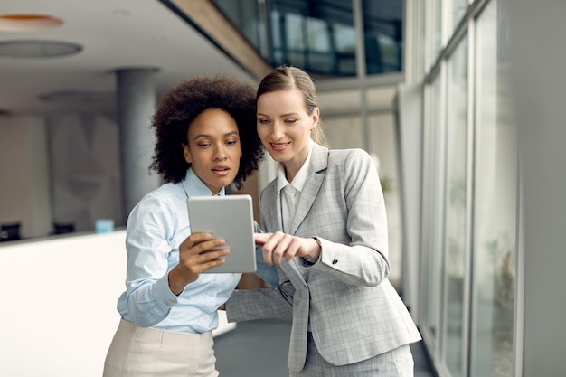 Deux femmes d'affaires utilisant une tablette numérique dans un couloir