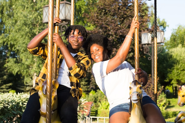 Deux femmes afro-américaines heureuses dans un parc sur un manège en été