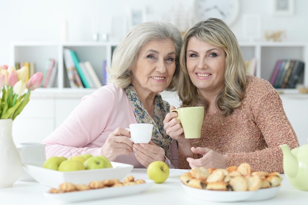 Deux femmes âgées buvant du thé avec des biscuits dans la cuisine