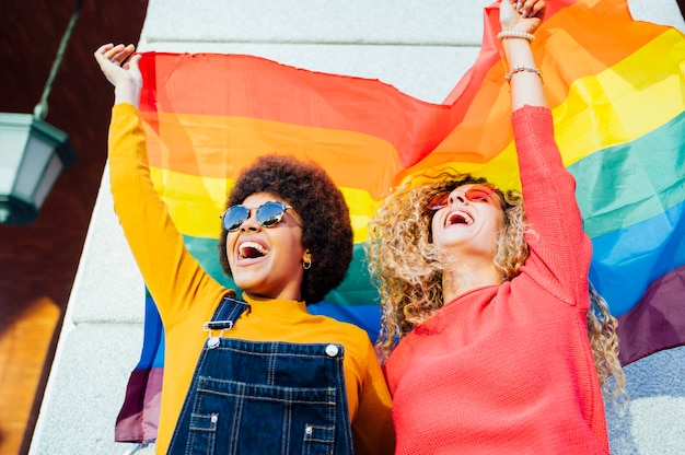 Deux femmes amis traîner dans la ville agitant des LGBT avec drapeau de fierté