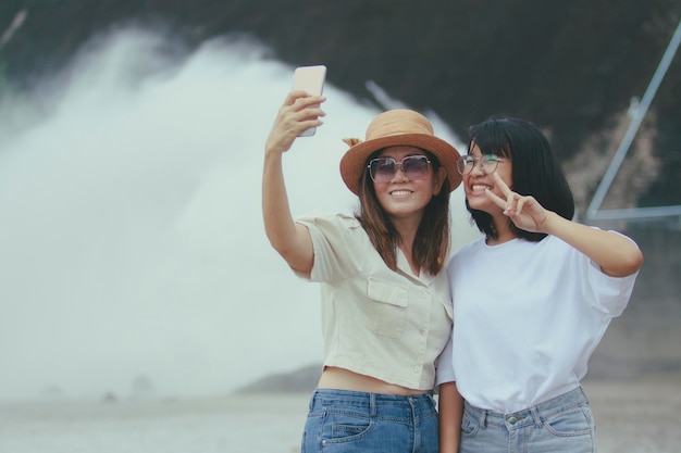 Deux femmes asiatiques gaies prenant une photo par smartphone