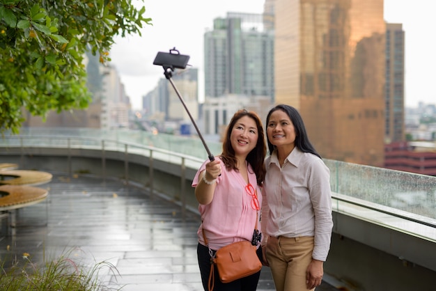 Deux femmes asiatiques matures ensemble contre vue sur la ville