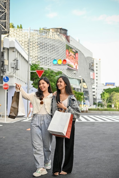 Deux femmes asiatiques ravies avec leurs sacs à provisions aiment marcher dans la rue commerçante