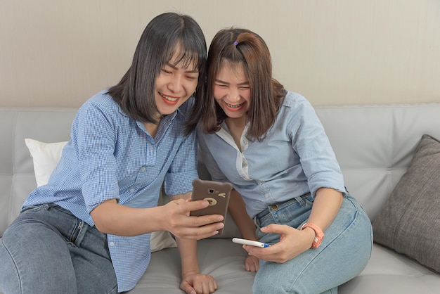 Deux femmes asiatiques utilisent un téléphone intelligent pour vérifier leurs e-mails