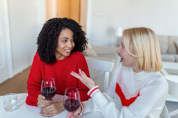 Deux femmes assises sur un canapé en train de rire dans un loft confortable avec du vin