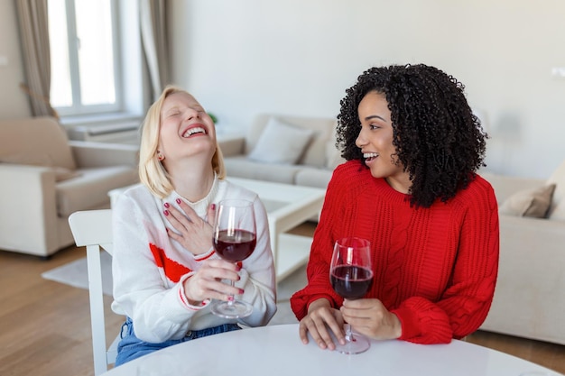 Deux femmes assises sur un canapé en train de rire dans un loft confortable avec du vin