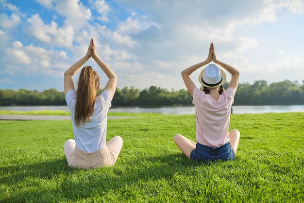 Deux femmes assises en position du lotus sur l'herbe verte