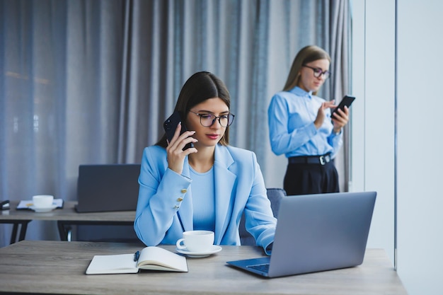 Deux femmes au bureau travaillent et font des affaires Femme d'affaires au bureau avec des lunettes et un téléphone