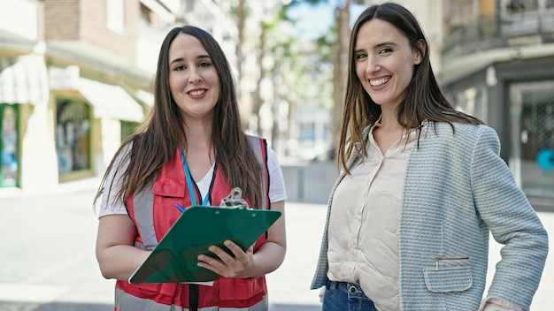 Deux femmes ayant une entrevue d'enquête écrivant sur le presse-papiers dans la rue