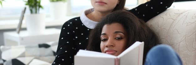 Photo deux femmes sur le canapé lisent un livre