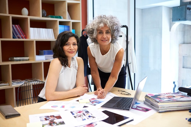 Deux femmes créatives travaillant au bureau à la recherche d'une caméra