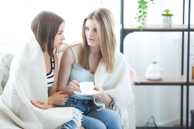 Deux femmes discutant sur le canapé à l'intérieur.