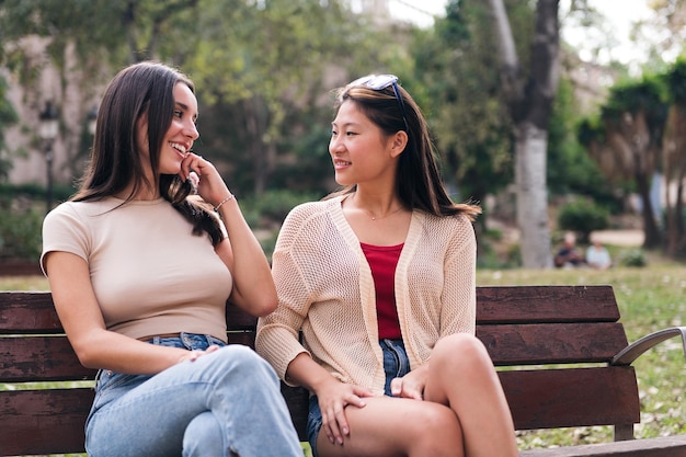 Deux femmes discutant heureux assis sur un banc de parc