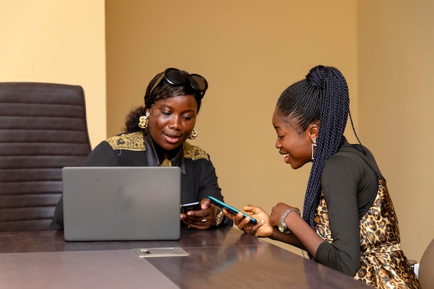 deux femmes diverses engagées dans une conversation tout en regardant un téléphone portable à une table