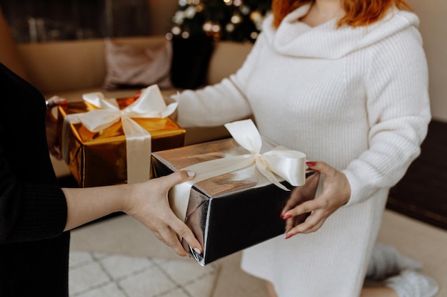 deux femmes échangent des cadeaux de Noël sur le fond d'un arbre de Noël