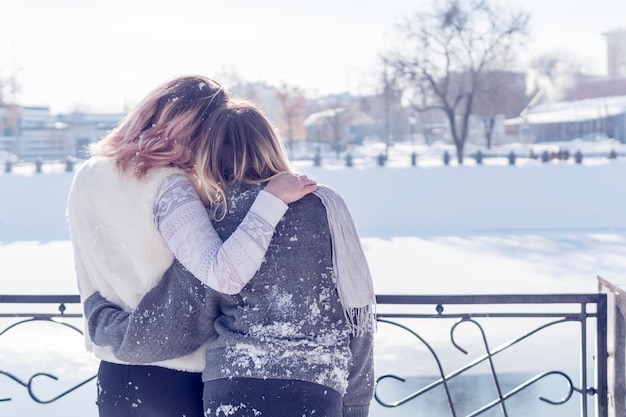 Deux femmes embrassées se tiennent près de la rivière gelée, vue arrière