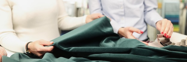 Deux femmes examinent le tissu du concept de couture personnalisé de couleur vert émeraude