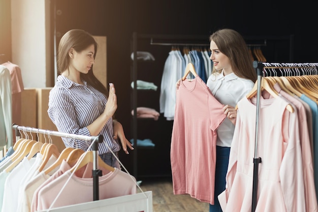 Deux femmes faisant du shopping. Jeunes filles choothing vêtements au showroom