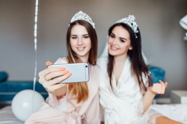 Deux femmes font un selfie dans la chambre, organisent une bonne fête de poule