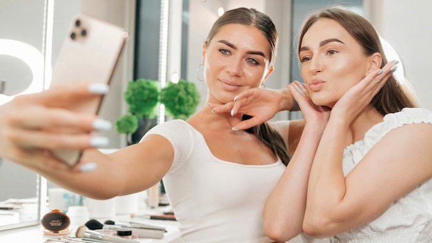 Deux femmes heureuses prennent un selfie dans un salon de beauté